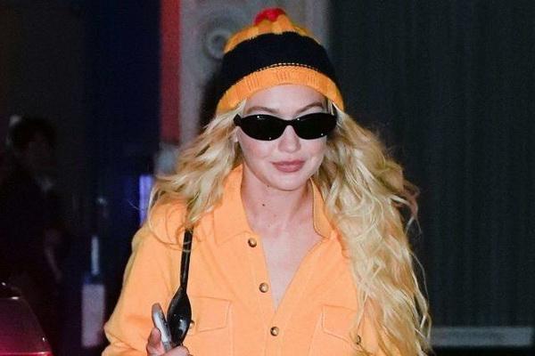 Gigi Hadid difoto mengenakan setelan boiler oranye longgar yang dilengkapi dengan topi bergaris oranye dan biru tua. (FOTO: GC IMAGE) 