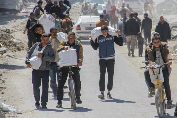 Warga Palestina membawa bantuan yang diturunkan dari truk, di Kota Gaza, 23 Maret 2024. REUTERS 