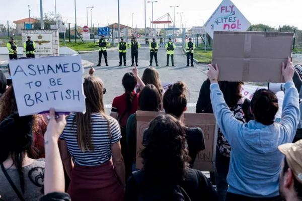 Pengunjuk rasa perdamaian menghadapi polisi yang berjaga di depan pangkalan RAF Akrotiri dekat Limassol, saat mereka berunjuk rasa menentang dugaan penggunaannya untuk memasok perang Israel di Gaza, klaim yang dibantah oleh Inggris, pada 14 Januari 2024. (FOTO: AFP) 