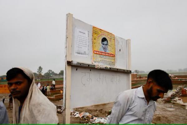 Orang-orang berdiri di dekat poster pengkhotbah Surajpal, di lokasi kongregasi agama Hindu di distrik Hathras negara bagian utara Uttar Pradesh, India, 3 Juli 2024. REUTERS 