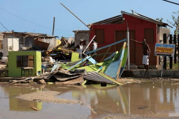 Seorang pria memberi isyarat di samping rumah yang hancur setelah berlalunya Badai Beryl, di Clarendon, Jamaika 4 Juli 2024. REUTERS 
