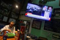 Seorang bartender berdiri di samping TV yang menayangkan berita penangkapan gembong narkoba Meksiko di sebuah bar di Mexico City, Meksiko, 25 Juli 2024. REUTERS