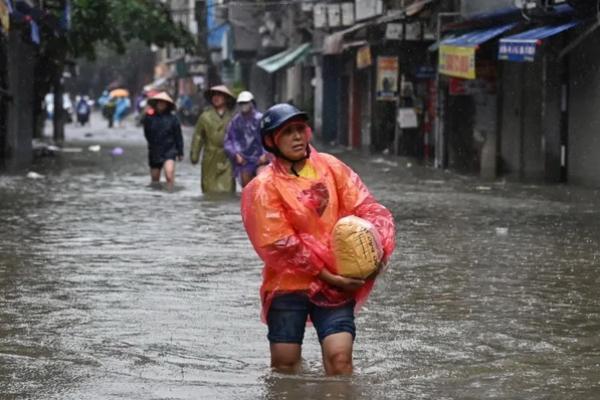 Seorang perempuan membawa sekantong beras di Hanoi, pada 11 September 2024, saat hujan lebat akibat Topan Yagi menyebabkan banjir di Vietnam utara. (FOTO: AFP) 