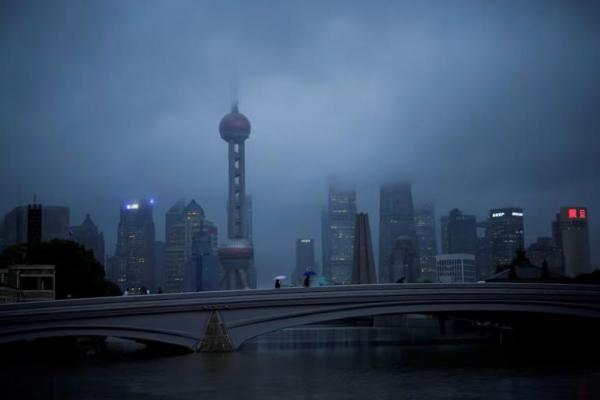 Orang-orang berjalan dengan payung di jembatan di tengah Topan Muifa, di Shanghai, Tiongkok, 14 September 2022. REUTERS 