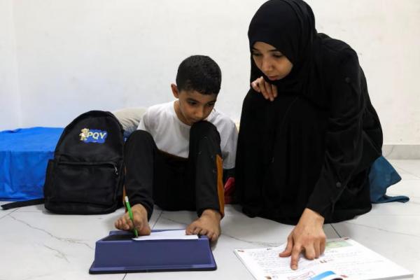 Mahmoud Ajjour, seorang anak yang terluka yang dievakuasi dari Gaza, bersama ibunya yang  mengajarinya menulis menggunakan kakinya, di Doha, Qatar, 11 September 2024. REUTERS 