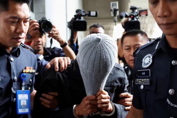 Seorang pria yang terkait dengan Global Ikhwan Service and Business Holdings menutupi wajahnya saat dikawal polisi di pengadilan Putrajaya, Malaysia, 18 September 2024. REUTERS 