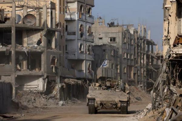 Sebuah kendaraan lapis baja melaju sementara bangunan-bangunan yang rusak terlihat di latar belakang, di Jalur Gaza, 13 September 2024. REUTERS 