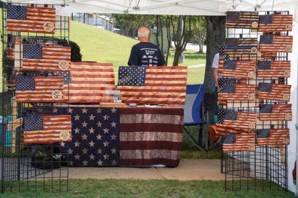 Seorang pria dengan stan yang menjual bendera kayu Amerika di festival pedesaan Pigs and Peaches di Kennesaw, Georgia, AS, 17 Agustus 2024. REUTERS 