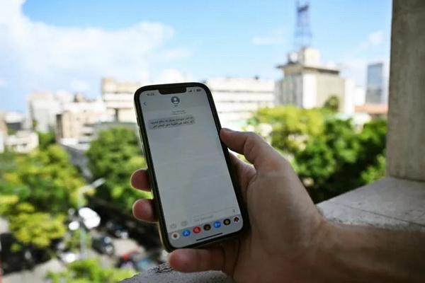 Seorang pria Lebanon memeriksa pesan yang diterima di ponselnya di Beirut pada 23 September 2024, yang menyerukan orang-orang untuk mengungsi dari wilayah tempat Hizbullah menyembunyikan senjatanya. (FOTO: AFP) 