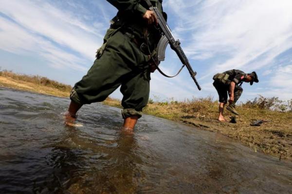 Seorang prajurit dari Tentara Kemerdekaan Kachin dan rekannya menyeberangi sungai menuju garis depan di Laiza, negara bagian Kachin, 29 Januari 2013. REUTERS 