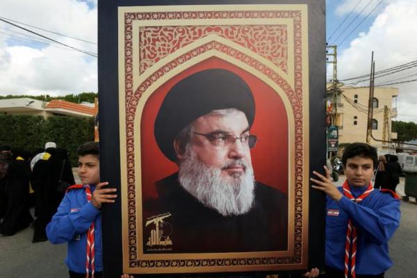 Pramuka membawa foto pemimpin Hizbullah Sayyed Hassan Nasrallah saat pemakaman anggota Hizbullah Ali Mohamed Chalbi, di Kfar Melki, Lebanon 19 September 2024. REUTERS 