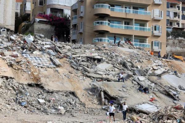 Orang-orang memeriksa kerusakan di lokasi serangan Israel hari Minggu di kota Ain Deleb, Lebanon selatan 30 September 2024. REUTERS 