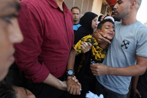 Seorang anak laki-laki dihibur saat ia berduka di dekat jenazah ayahnya dan warga Palestina lainnya, di Rumah Sakit Martir Al-Aqsa di Deir Al-Balah di Jalur Gaza tengah, 9 Oktober 2024. REUTERS 