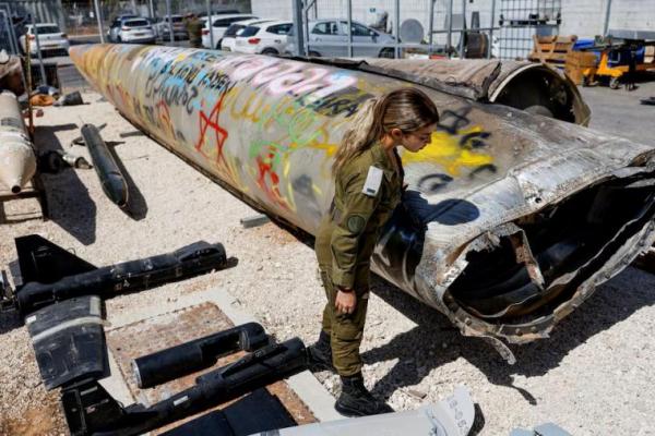 Seorang tentara Israel berdiri di samping sisa-sisa rudal balistik Emad di pangkalan militer Julis, Israel selatan, 9 Oktober 2024. REUTERS 