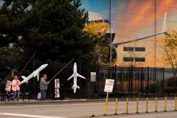 Pekerja Boeing Maria Hamshaw dan Tim Mattingly, memegang pesawat tiup dekat pintu masuk fasilitas produksi Boeing di Renton, Washington, AS, 11 Oktober 2024. REUTERS 