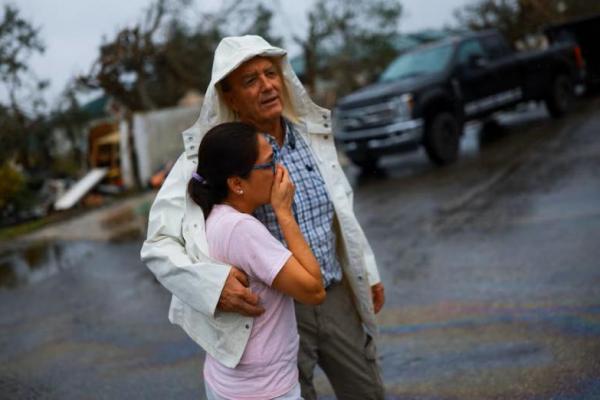 Jeff Schorner memeluk anggota keluarganya di samping bisnisnya yang hancur akibat Badai Milton, di Lakewood Park, St. Lucie County, Florida, AS, 11 Oktober 2024. REUTERS 