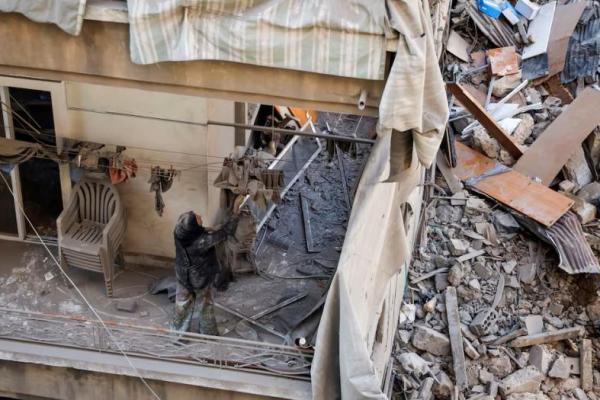 Maha Haddad, ibu mertua Ahmed Al-Khatib membersihkan puing-puing di apartemen mereka yang rusak di lokasi serangan di Beirut, Lebanon, 11 Oktober 2024. REUTERS 