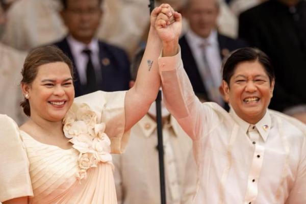 Wakil Presiden yang baru terpilih, Sara Duterte, mengangkat tangan Presiden Ferdinand Marcos Jr., saat pelantikan di Museum Nasional di Manila, Filipina, 30 Juni 2022. REUTERS 