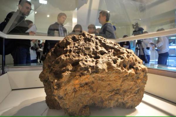 Reporter berkumpul di sekitar sepotong meteorit, yang menurut ilmuwan diangkat dari dasar Danau Chebarkul, di museum lokal Chelyabinsk, 18 Oktober 2013. REUTERS 