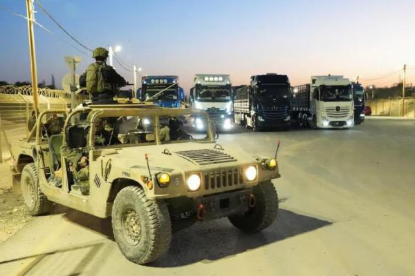 Tentara Israel duduk di kendaraan militer di dekat truk yang membawa bantuan kemanusiaan menuju Jalur Gaza, di Persimpangan Erez di Israel selatan, 21 Oktober 2024. REUTERS 