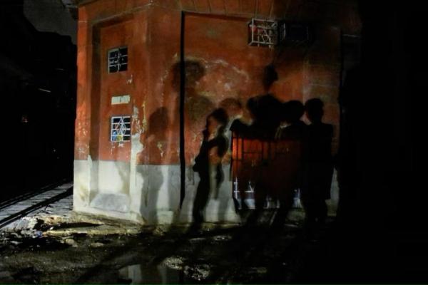 Bayangan orang-orang terlihat di dinding melalui lampu mobil yang lewat, di Havana, Kuba 21 Oktober 2024. REUTERS 