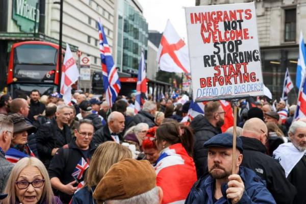 Seorang pria memegang plakat saat orang-orang menghadiri protes antiimigrasi, di London, Inggris, 26 Oktober 2024. REUTERS 