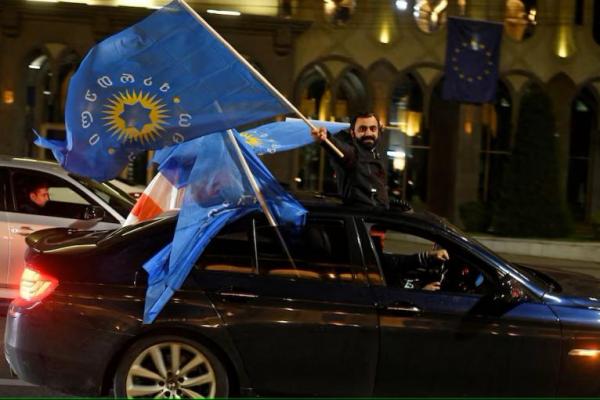 Seorang pendukung partai Mimpi Georgia mengibarkan bendera partai, Tbilisi, 26 Oktober 2024. REUTERS 