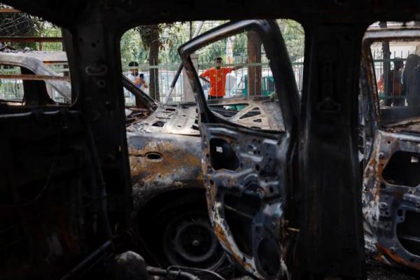 Orang-orang berdiri di dekat mobil-mobil yang dirusak di Kantor Polisi Mohammadpur, di Dhaka, Bangladesh, 6 Agustus 2024. REUTERS 