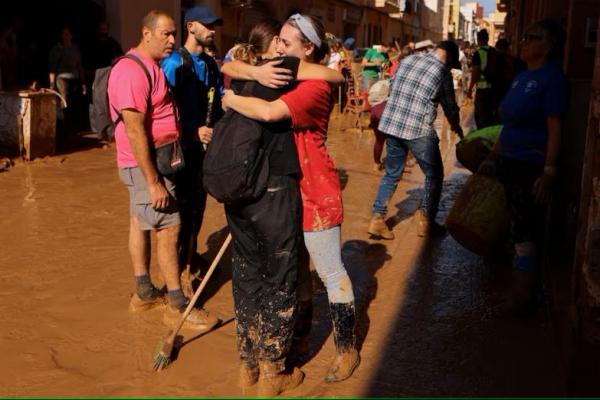 Orang-orang berpelukan saat mereka berdiri di jalan yang tertutup lumpur di Paiporta, dekat Valencia, Spanyol, 1 November 2024. REUTERS 