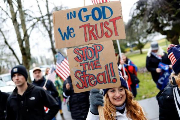 Seorang pengunjuk rasa memegang plakat saat kampanye Presiden AS Donald Trump di Oregon State Capitol di Salem, Oregon, AS, 6 Januari 2021. REUTERS 