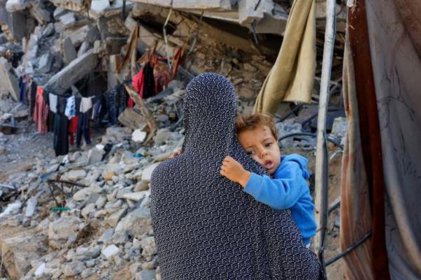 Seorang wanita Palestina menggendong anaknya di dekat reruntuhan rumah yang hancur akibat serangan militer Israel, di Khan Younis di Jalur Gaza selatan, 4 November 2024. REUTERS 