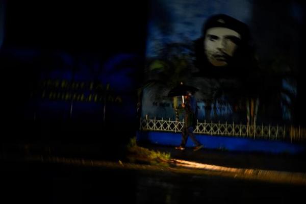 Seorang pria berjalan melewati gambar mendiang pahlawan revolusioner Ernesto Guevara saat listrik padam di Havana, Kuba 7 November 2024. REUTERS 