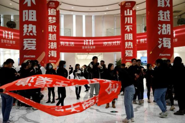 Orang-orang berdiri di dekat spanduk untuk festival belanja Hari Jomblo di kantor pusat JD.com, di Beijing, Tiongkok, 9 November 2021. REUTERS 