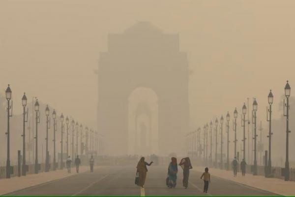 Wanita berjalan di jalan dekat Gerbang India saat langit diselimuti kabut asap karena polusi udara, di New Delhi, India, 19 November 2024. REUTERS 