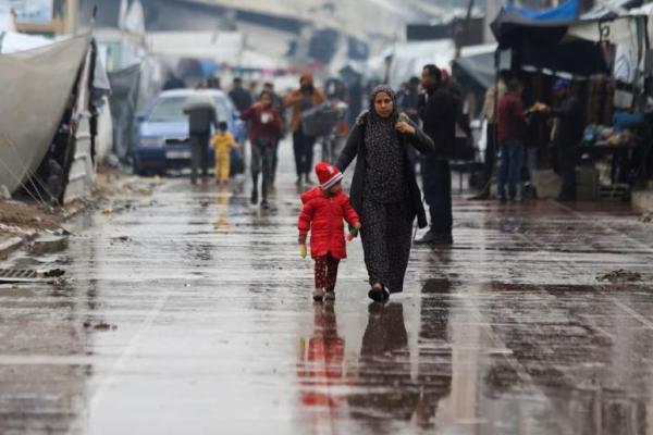 Warga Palestina yang mengungsi berjalan di dekat tenda setelah hujan, di tengah konflik Israel-Hamas, di Kota Gaza, 24 November 2024. REUTERS 