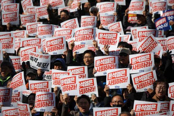 Demonstran mengangkat plakat bertuliskan Mundur Presiden Yoon Suk Yeol saat orang-orang dan anggota parlemen menghadiri rapat umum di Seoul, 4 Desember 2024. REUTERS 