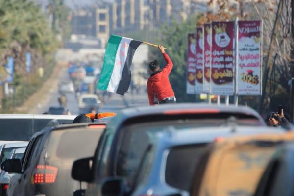 Seorang anak laki-laki memegang bendera oposisi Suriah di Aleppo, 30 November 2024. REUTERS 