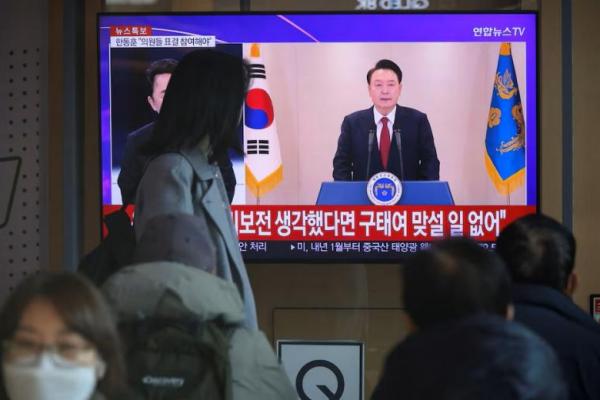 Orang-orang menonton layar TV, yang menyiarkan Presiden Korea Selatan Yoon Suk Yeol menyampaikan pidato di Seoul, Korea Selatan, 12 Desember 2024. REUTERS 