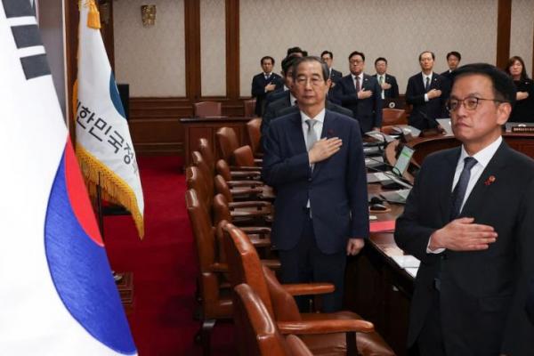 Presiden sementara Korea Selatan Han Duck-soo memberi hormat kepada bendera nasional di kompleks pemerintah di Seoul, Korea Selatan, 14 Desember 2024. Yonhap via REUTERS 