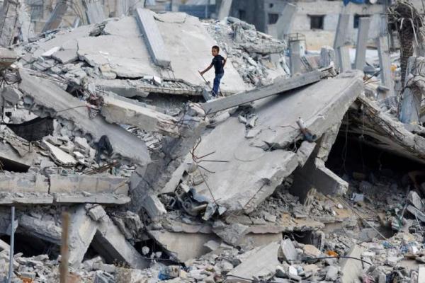 Seorang anak laki-laki Palestina berdiri di atas reruntuhan rumah yang hancur di Khan Younis di Jalur Gaza selatan 7 Oktober 2024. REUTERS 