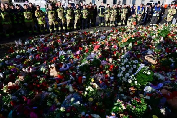 Anggota pemadam kebakaran Magdeburg berdiri di tugu peringatan darurat di luar Johanniskirche (Gereja Johannes), dekat lokasi serangan penabrakan mobil di pasar Natal di Magdeburg, Jerman timur, pada 22 Desember 2024. (FOTO: AFP) 