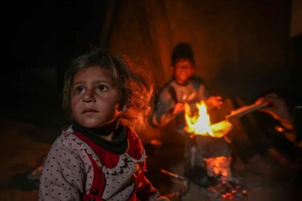 Cucu-cucu Reda Abu Zarada duduk di dekat api unggun di kamp di tepi laut di Khan Younis, Jalur Gaza. (FOTO: AP) 