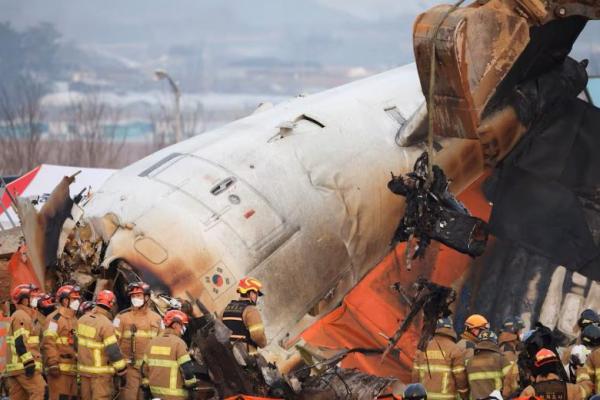 Sebuah ekskavator digunakan untuk mengangkat kursi yang terbakar dari pesawat di Bandara Internasional Muan, Korea Selatan, 29 Desember 2024. REUTERS 