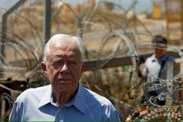 Mantan Presiden AS Jimmy Carter berdiri di depan penghalang Israel yang kontroversial selama kunjungan ke desa Bilin di Tepi Barat dekat Ramallah, 27 Agustus 2009. REUTERS 