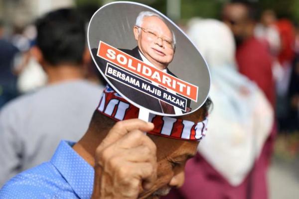 Seorang pendukung mantan Perdana Menteri Malaysia Najib Razak memegang kipas tangan bergambar dirinya di luar Pengadilan Banding, di Putrajaya, Malaysia, 6 Januari 2025. REUTERS 