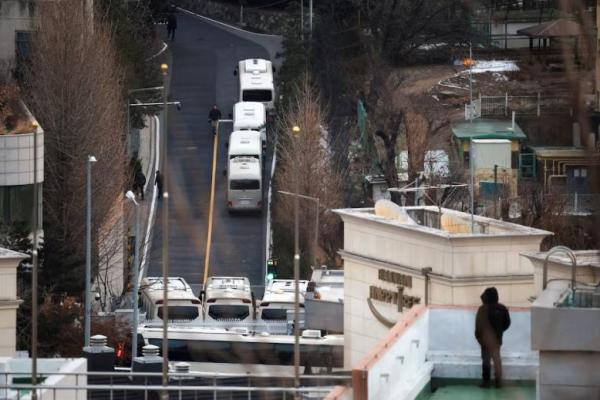 Seorang pria berdiri di atap gedung saat melihat pintu masuk kediaman resmi Presiden Korea Selatan yang dimakzulkan Yoon Suk Yeol, di Seoul, Korea Selatan, 8 Januari 2025. REUTERS 