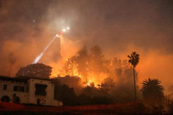 Sebuah helikopter melakukan penyemprotan air, di perbukitan yang menghadap ke kawasan Hollywood di Los Angeles, California, AS, 8 Januari 2025. REUTERS 