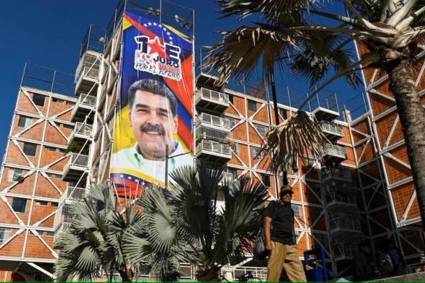 Seorang pria berjalan melewati gedung dan tanda dengan gambar Presiden Venezuela Nicolas Maduro sebelum dia dilantik di Caracas, Venezuela 8 Januari 2025. REUTERS 