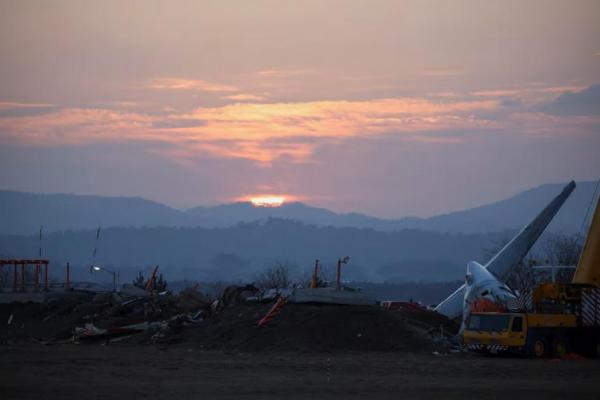 Matahari terbit di balik puing-puing dan reruntuhan pesawat di Bandara Internasional Muan, Korea Selatan, 31 Desember 2024. REUTERS 