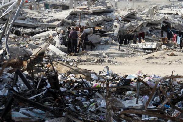 Warga Palestina berdiri di antara puing-puing rumah yang hancur dalam serangan Israel sebelumnya, di Kota Gaza, 15 Januari 2025. REUTERS 